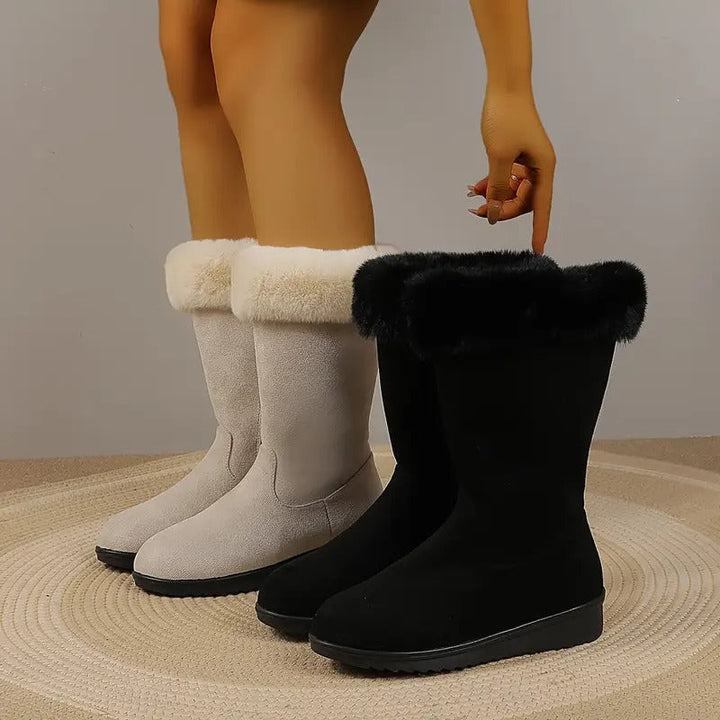 Wadenhohe Emilia Winterstiefel in Beige und Schwarz mit weichem Fellabschluss und flacher Profilsohle.