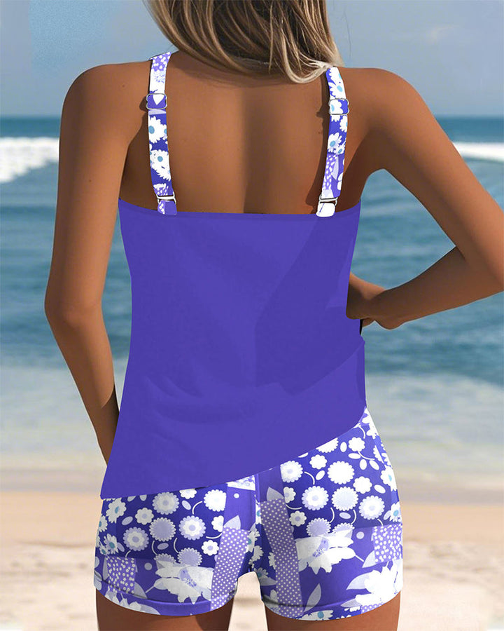 Blauer Emma Tankini von hinten mit geblümten Shorts am Strand