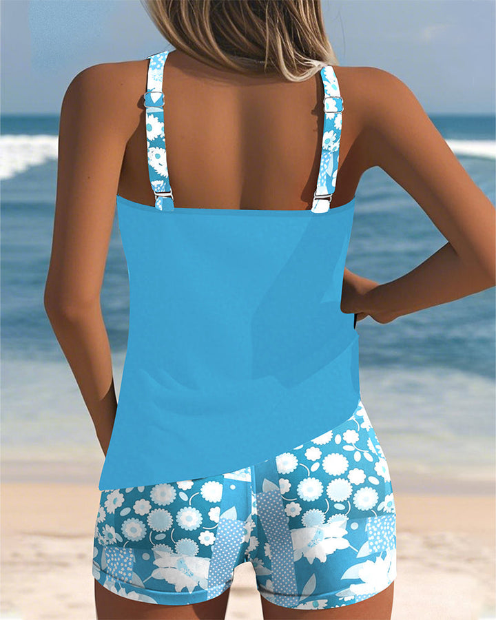 Rückansicht des blauen Emma Tankinis mit geblümten Shorts am Strand