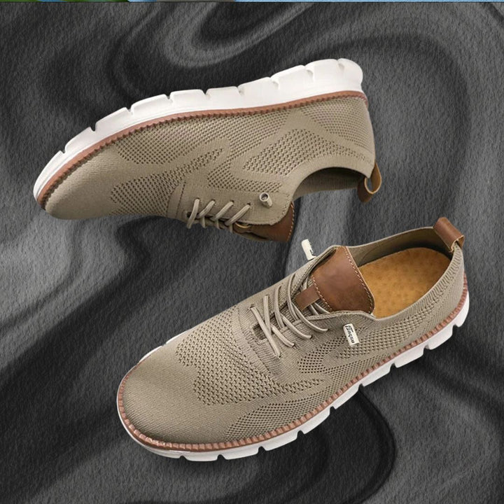 Beige Herren-Mesh-Sneaker mit braunen Lederoptik-Details und weißer, flexibler Laufsohle auf dunklem Hintergrund.