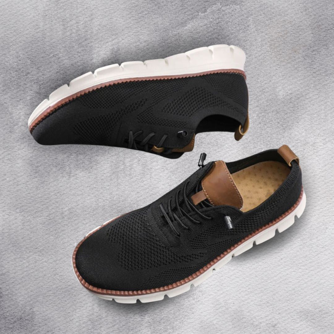 Schwarzer Herren-Mesh-Sneaker mit braunen Lederoptik-Details und weißer, flexibler Laufsohle auf grauem Hintergrund.