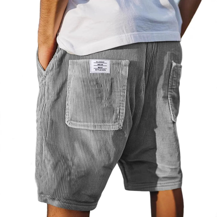 Graue Herren-Samtshorts im Relaxed Fit mit elastischem Bund und aufgesetzter Gesäßtasche mit Label-Patch.