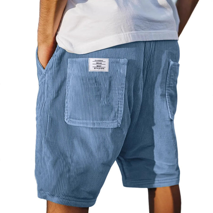Blaue Herren-Samtshorts im Relaxed Fit mit elastischem Bund und aufgesetzter Gesäßtasche mit Label-Patch.