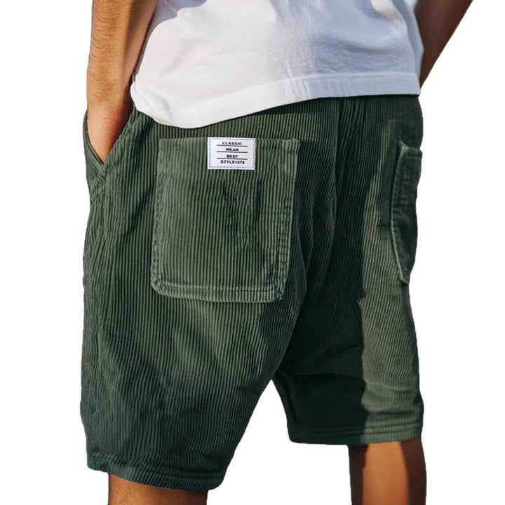 Dunkelgrüne Herren-Shorts aus weichem Samt mit elastischem Bund, Relaxed Fit und aufgesetzter Gesäßtasche mit Label.