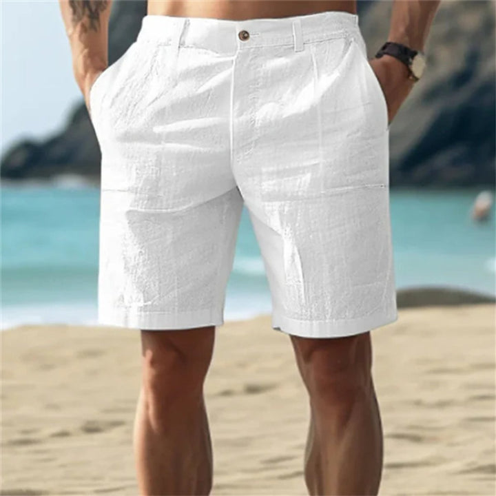 Weiße Herren-Leinenshorts mit elastischem Bund und Seitentaschen, getragen am Strand für einen lockeren Sommer-Look.