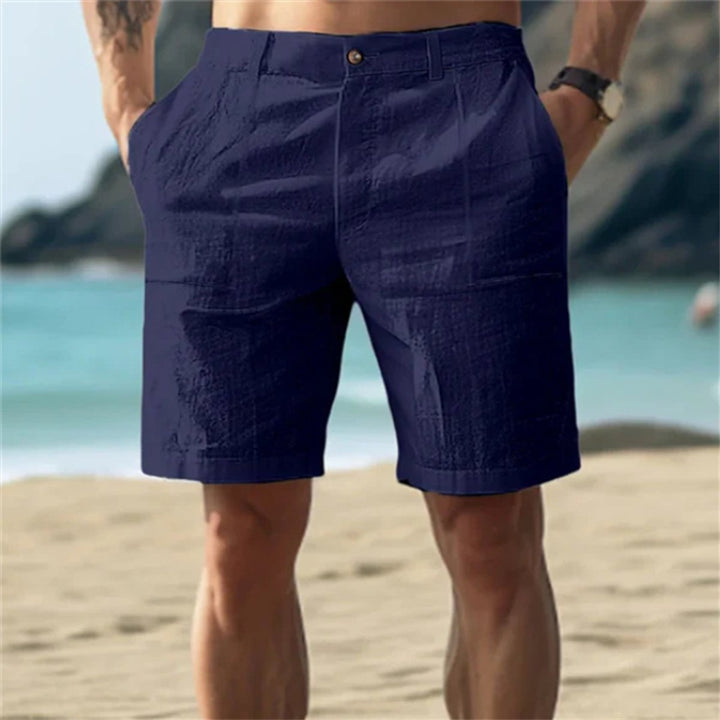 Dunkelblaue Herren-Leinenshorts mit elastischem Bund und Seitentaschen in lockerer Passform am Strand.