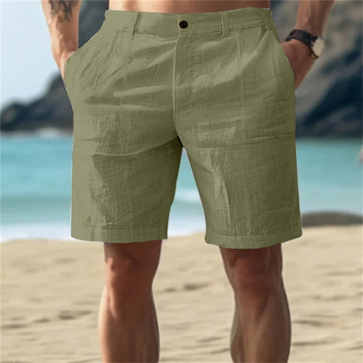 Olivgrüne Herren-Leinenshorts mit elastischem Bund und Seitentaschen in lockerer Passform am Strand.