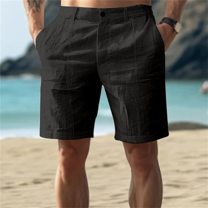 Schwarze Leinen-Shorts für Herren mit elastischem Bund und Seitentaschen in lockerer Passform am Strand.