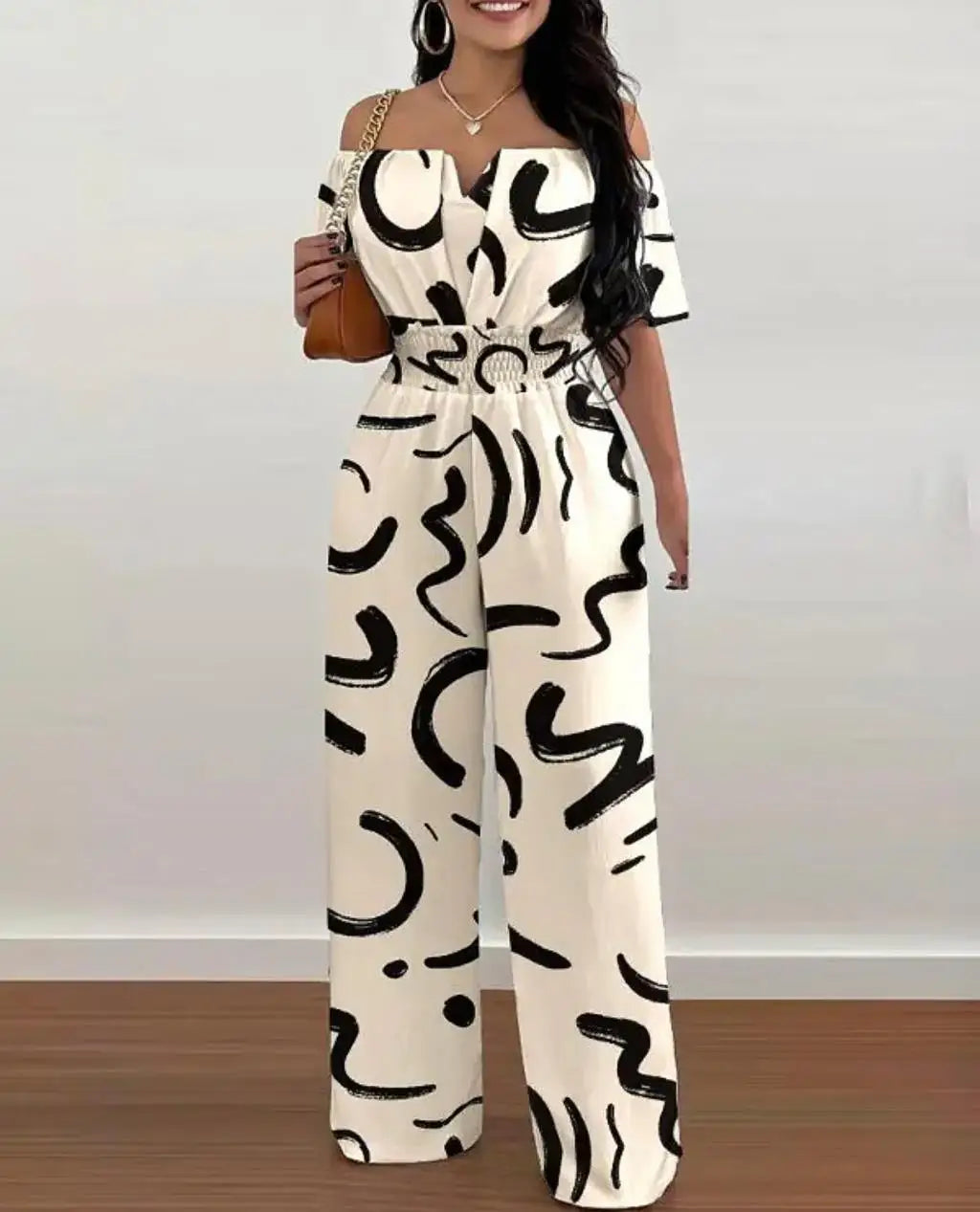Greta Off-Shoulder Jumpsuit mit weitem Bein, weiß mit schwarzem abstraktem Muster und betonter Taille.