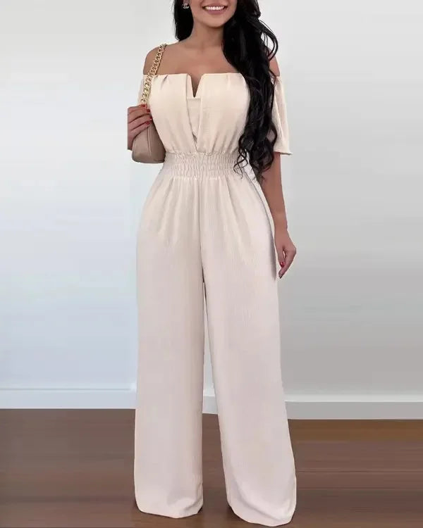 Beiger Off-Shoulder Jumpsuit mit weitem Bein, betonter Taille und strukturierter Stoffoptik.