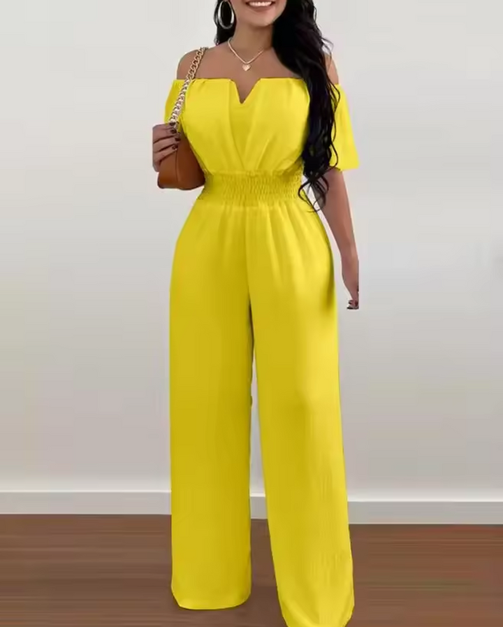 Gelber Greta Jumpsuit mit Off-Shoulder-Ausschnitt, betonter Taille und fließendem, weitem Bein.