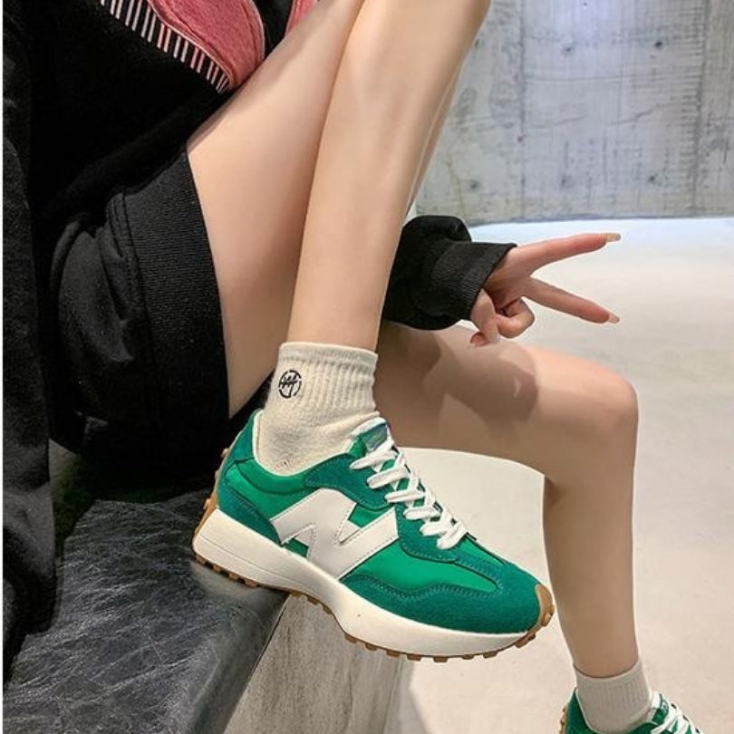Grüner Retro-Sneaker mit Wildleder-Details, Mesh-Einsätzen, weißem Logo-Patch und markanter Gummisohle.