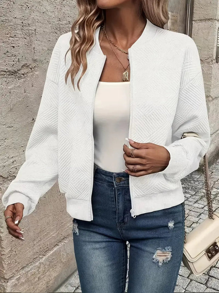 Weiße Strickjacke mit Reißverschluss, Stehkragen und strukturiertem Muster, kombiniert mit Jeans.