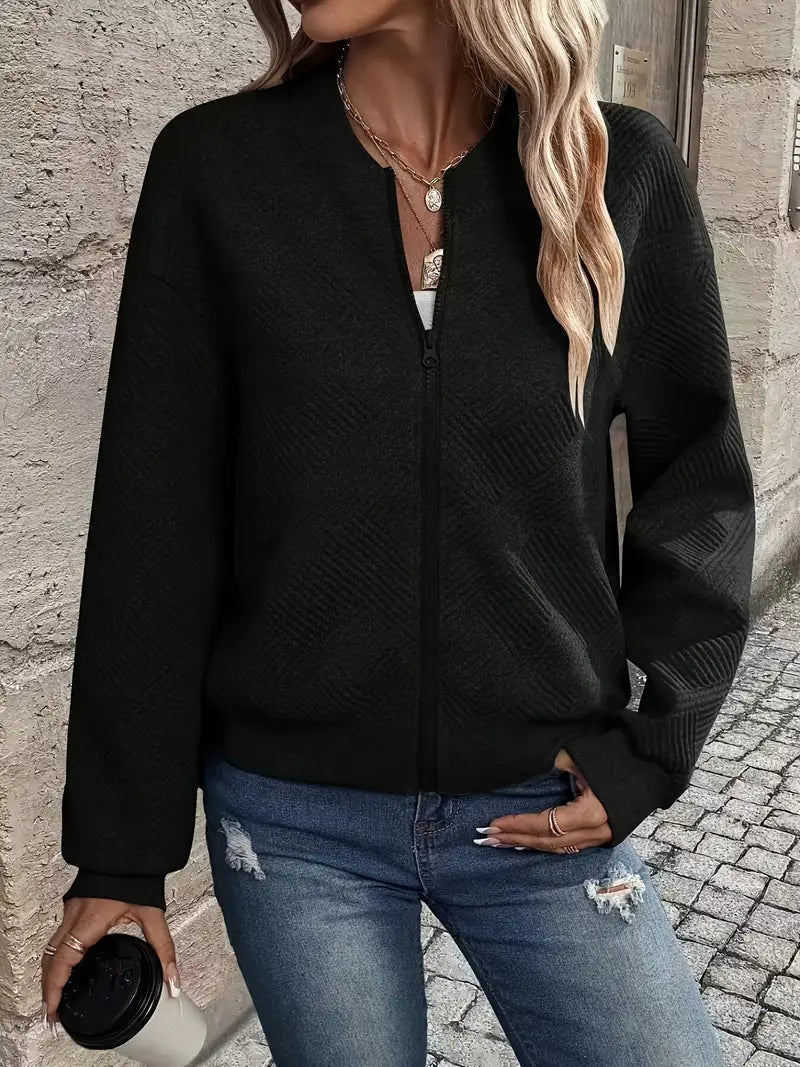 Schwarze Damen-Strickjacke mit Reißverschluss, Stehkragen und strukturiertem Strickmuster kombiniert mit Jeans.