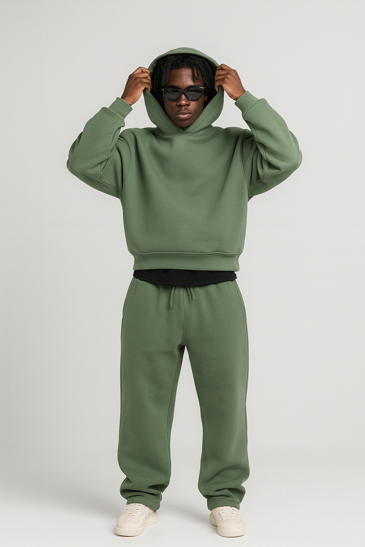 Mann trägt ein olivgrünes Baumwoll-Set aus Hoodie und Jogginghose mit Kordelzug und gerippten Bündchen.
