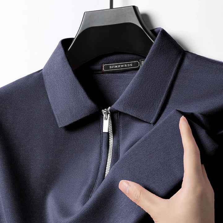 Dunkelblaues Herren-Poloshirt mit Reißverschluss, klassischem Kragen und feiner Piqué-Struktur auf einem Kleiderbügel.