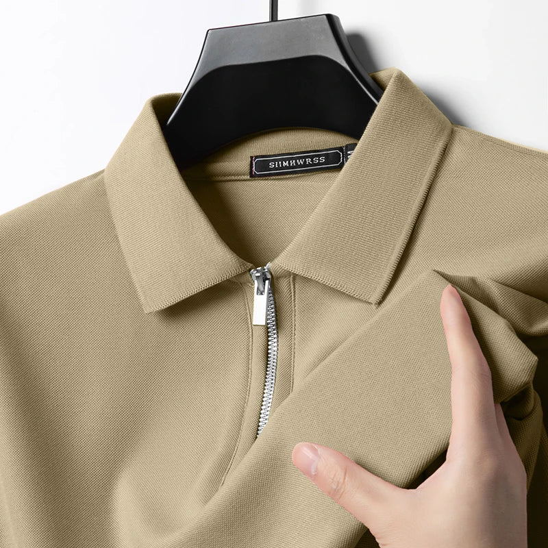 Beiges Herren-Poloshirt mit Reißverschluss, klassischem Kragen und feiner Piqué-Struktur auf einem Kleiderbügel.