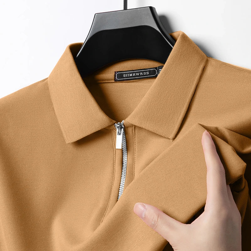 Beiges Herren-Poloshirt mit Reißverschluss, klassischem Kragen und feiner Piqué-Struktur an einem Kleiderbügel.