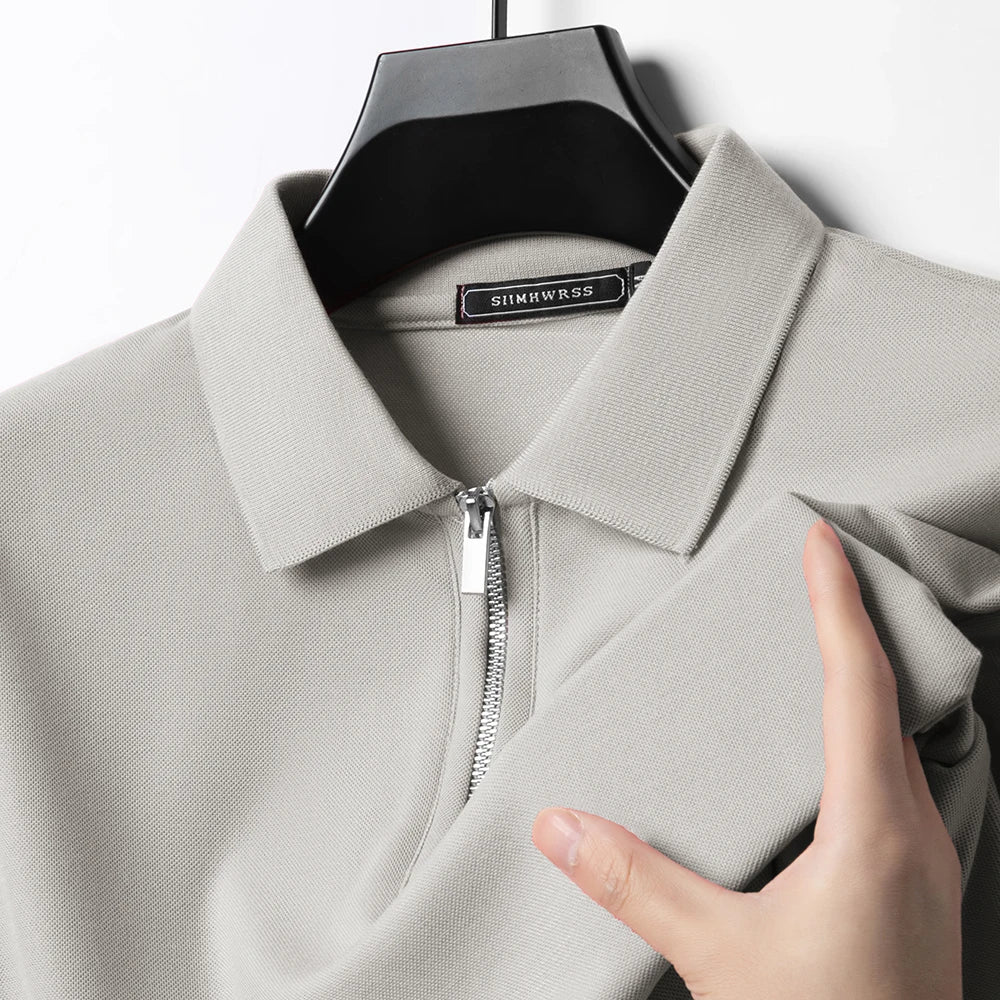 Hellgraues Herren-Poloshirt mit Reißverschluss, klassischem Kragen und feiner Piqué-Struktur auf einem Kleiderbügel.
