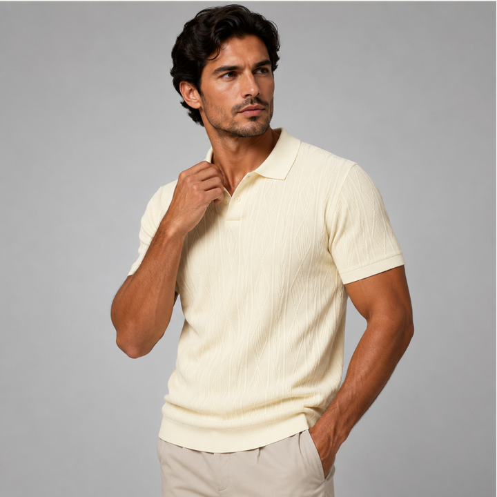 Beiges Herren-Strickpoloshirt mit Rautenmuster, Polokragen und kurzer Knopfleiste vor grauem Hintergrund.
