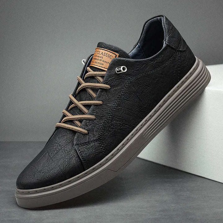 Schwarzer Herren-Sneaker mit strukturierter Oberfläche, braunen Schnürsenkeln und gerippter grauer Sohle.