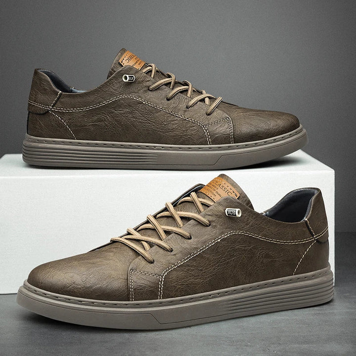 Braune Herren-Sneaker aus strukturiertem Lederimitat mit Schnürung, flacher Sohle und markanten Ziernähten.