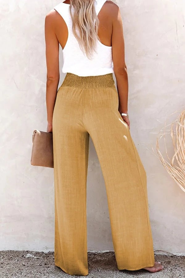 Beige High-Waist-Hose mit weitem Bein, gesmoktem Bund und fließendem Stoff, kombiniert mit weißem Top.