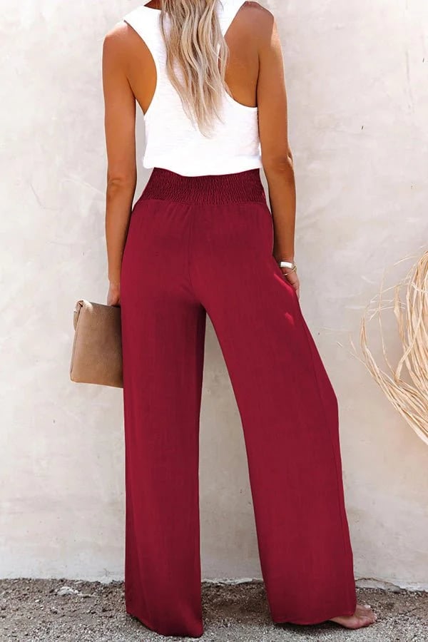Dunkelrote High-Waist-Hose mit weitem Bein, gesmoktem Bund und fließendem Stoff, kombiniert mit einem weißen Trägertop.