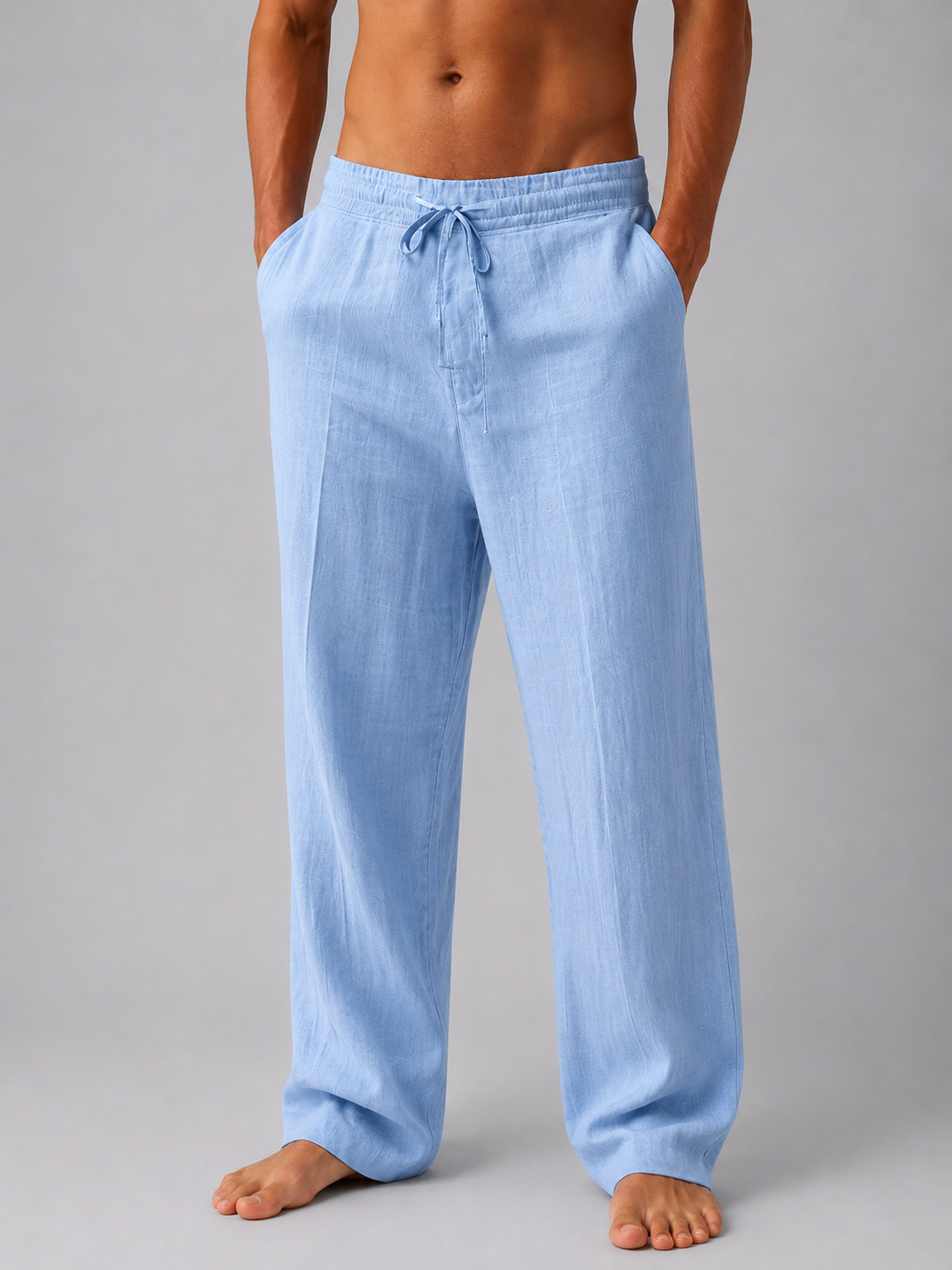 Hellblaue Herren-Leinenhose mit elastischem Bund, Kordelzug und entspannter Passform vor grauem Hintergrund.