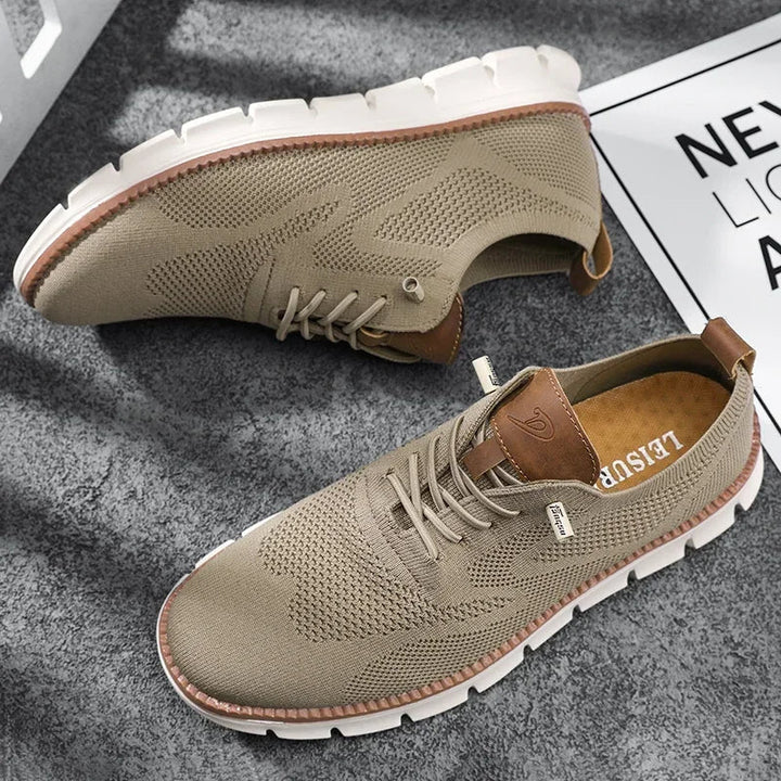 Beiger Herren-Sneaker aus atmungsaktivem Mesh mit Schnürung, braunen Lederdetails und flexibler weißer Laufsohle.