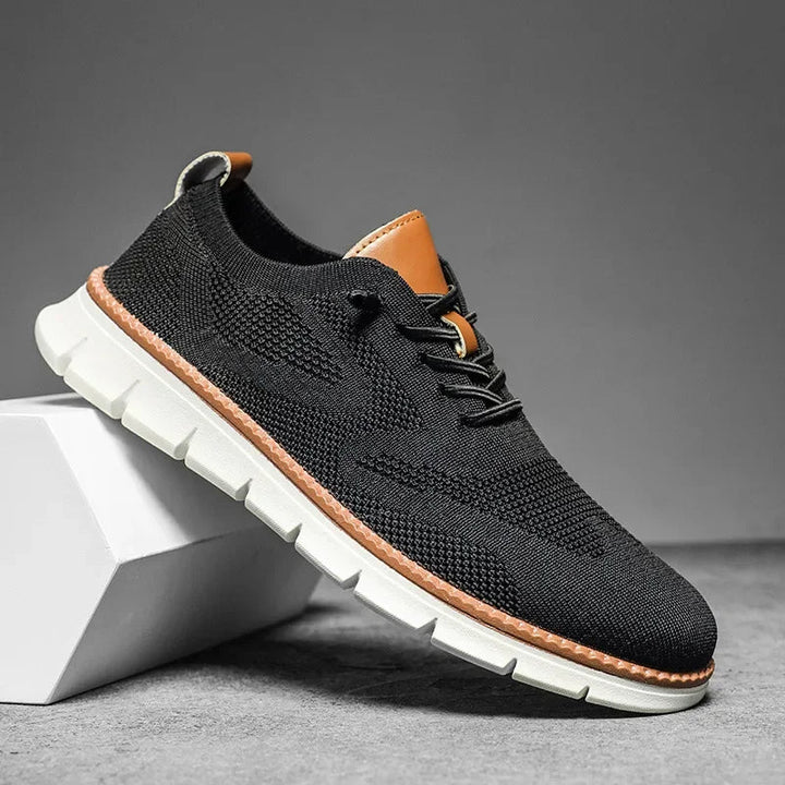 Schwarzer Herren-Mesh-Sneaker mit Schnürung, braunen Lederdetails und flexibler weißer Laufsohle.