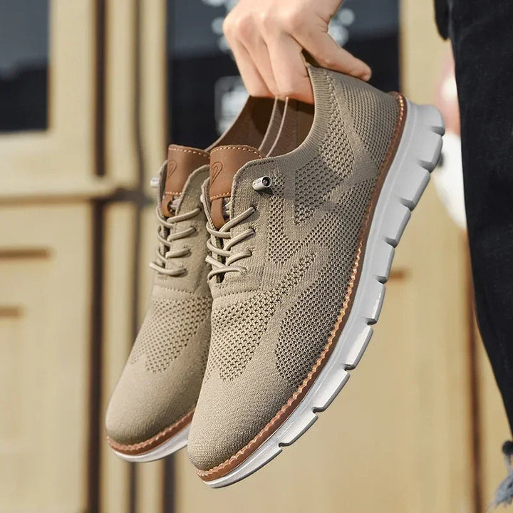 Beigefarbener Herren-Mesh-Sneaker mit braunen Lederdetails, Schnürung und flexibler weißer Laufsohle.