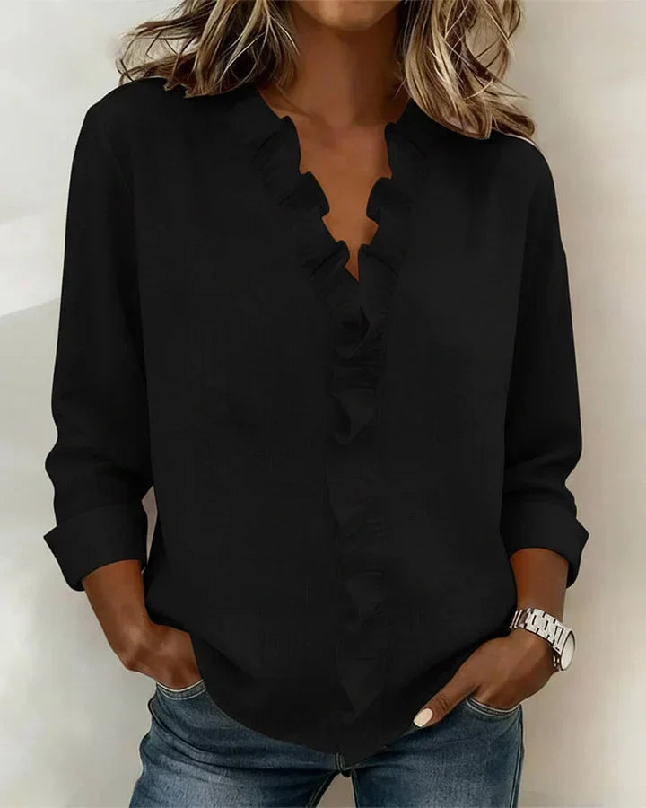 Schwarzes Katja Damen-Langarmtop mit V-Ausschnitt und eleganten Rüschen, getragen zu Jeans.