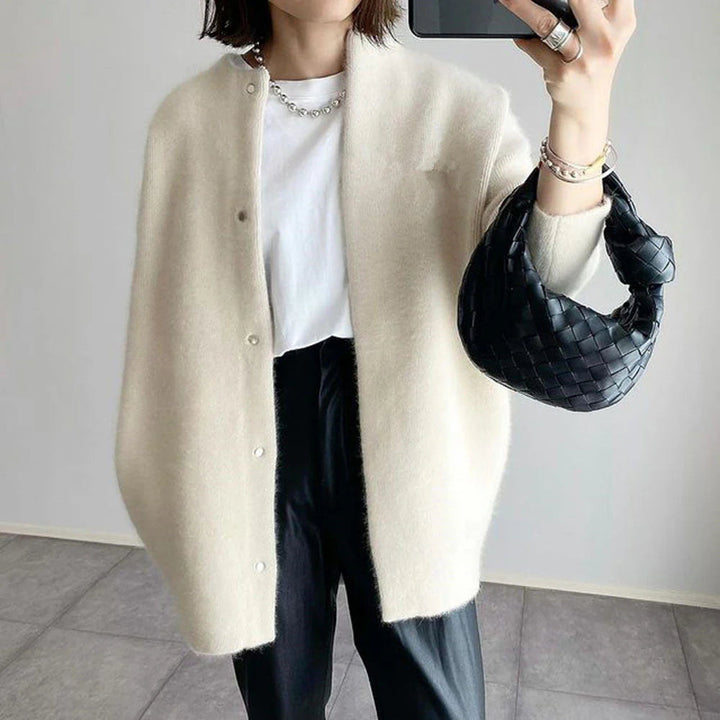Beige Oversize-Strickjacke mit Rundhals und Knopfleiste aus weichem Material für einen modernen, lässigen Lagen-Look.