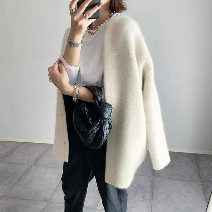 Cremeweiße Oversize-Strickjacke mit Rundhals und weicher Textur für einen eleganten, entspannten Lagen-Look.