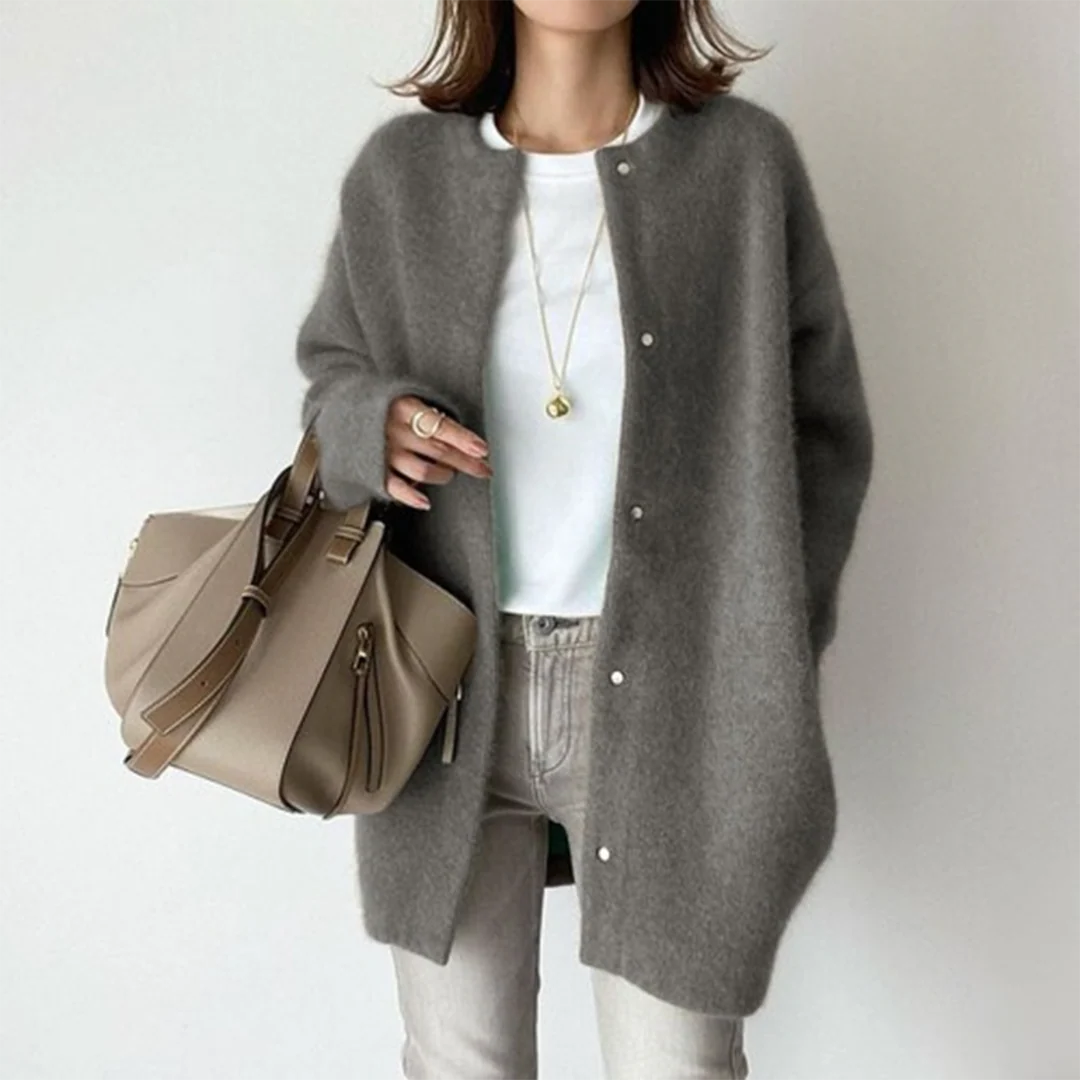 Graue Oversize-Strickjacke mit Rundhals und Knopfleiste für einen weichen, modernen Lagen-Look.