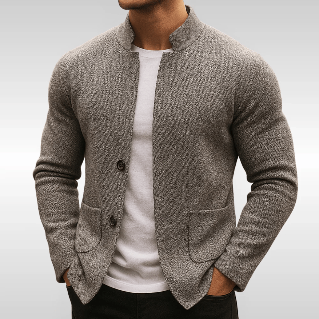 Graue Herren-Strickweste mit Stehkragen, Knopfleiste und aufgesetzten Taschen über einem weißen T-Shirt.