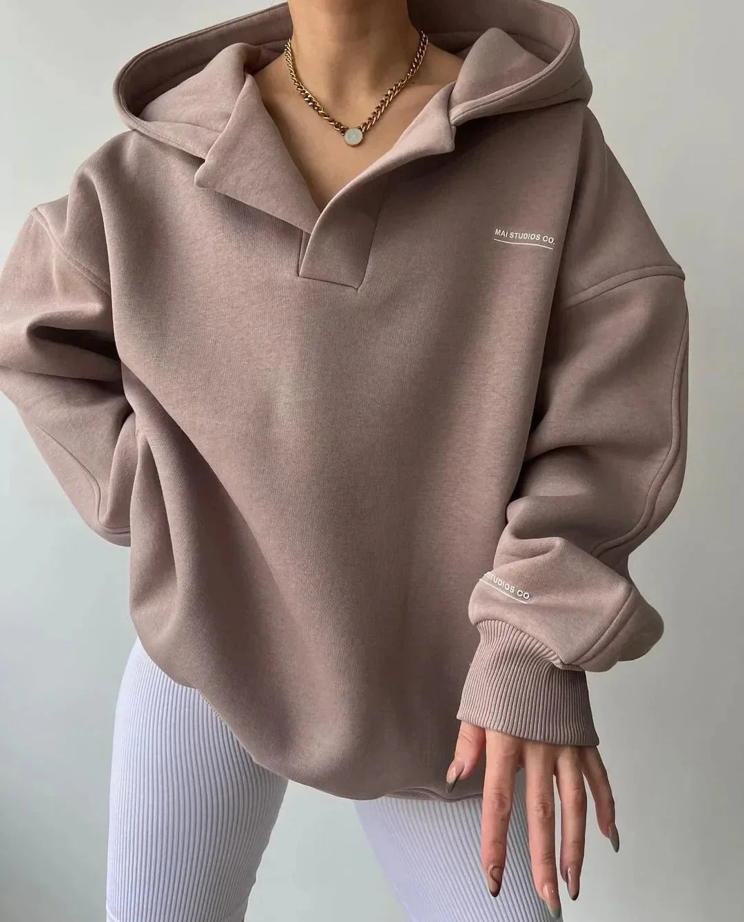 Beiger Oversized-Hoodie mit V-Ausschnitt, Kapuze, überschnittenen Schultern und dezentem Brust-Print.