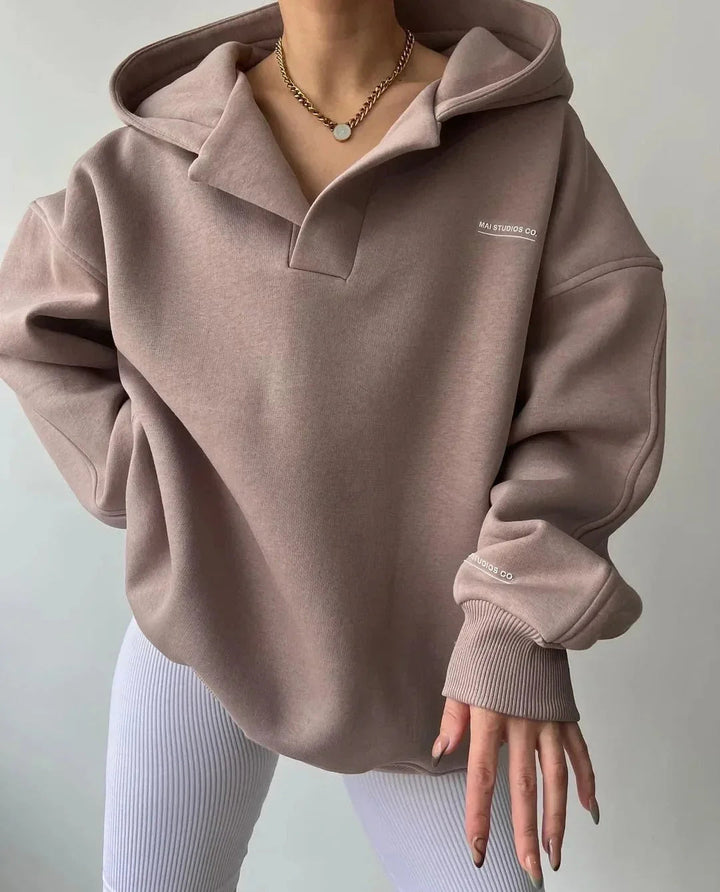 Beiger Oversized-Hoodie mit V-Ausschnitt, Kapuze, überschnittenen Schultern und dezentem Brust-Print.