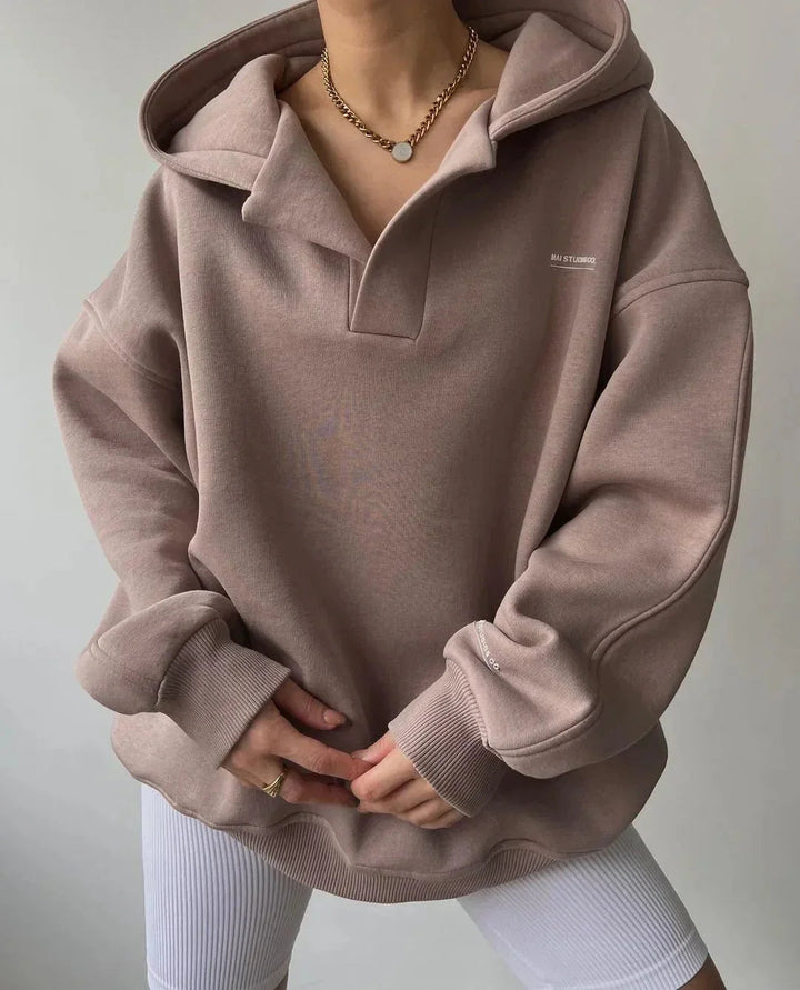Beiger Oversized-Hoodie mit V-Ausschnitt, Drop-Shoulder-Schnitt und dezentem Brust-Print aus weichem Sweatstoff.