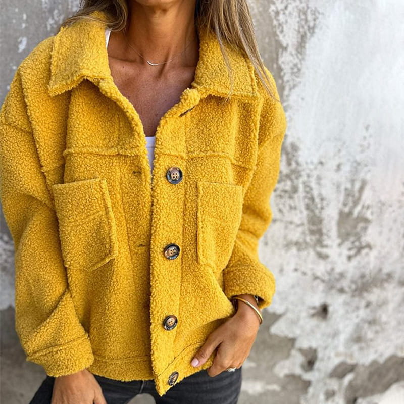 Senfgelbe Teddyjacke mit Knopfleiste, Umlegekragen und zwei Brusttaschen in flauschiger Optik.