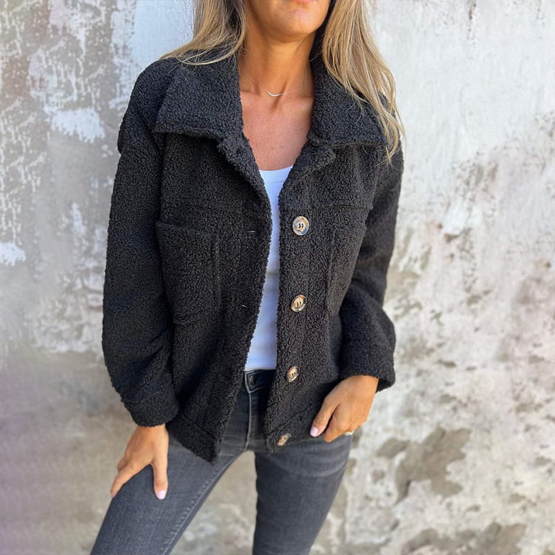 Schwarze Teddyjacke für Damen mit Knopfleiste, Umlegekragen und zwei Brusttaschen aus flauschigem Material.