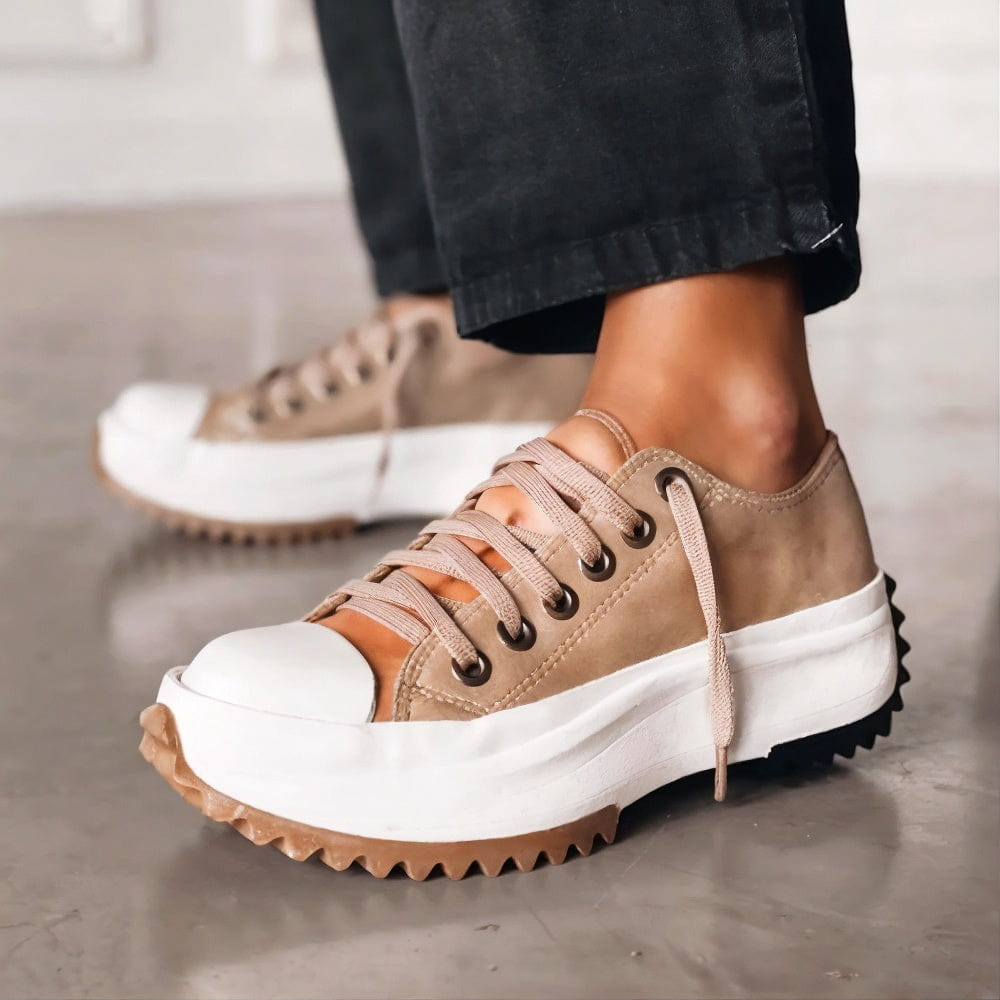 Beiger Damen-Plateau-Sneaker mit weißer Zehenkappe, Schnürung und markanter, gezackter Laufsohle.