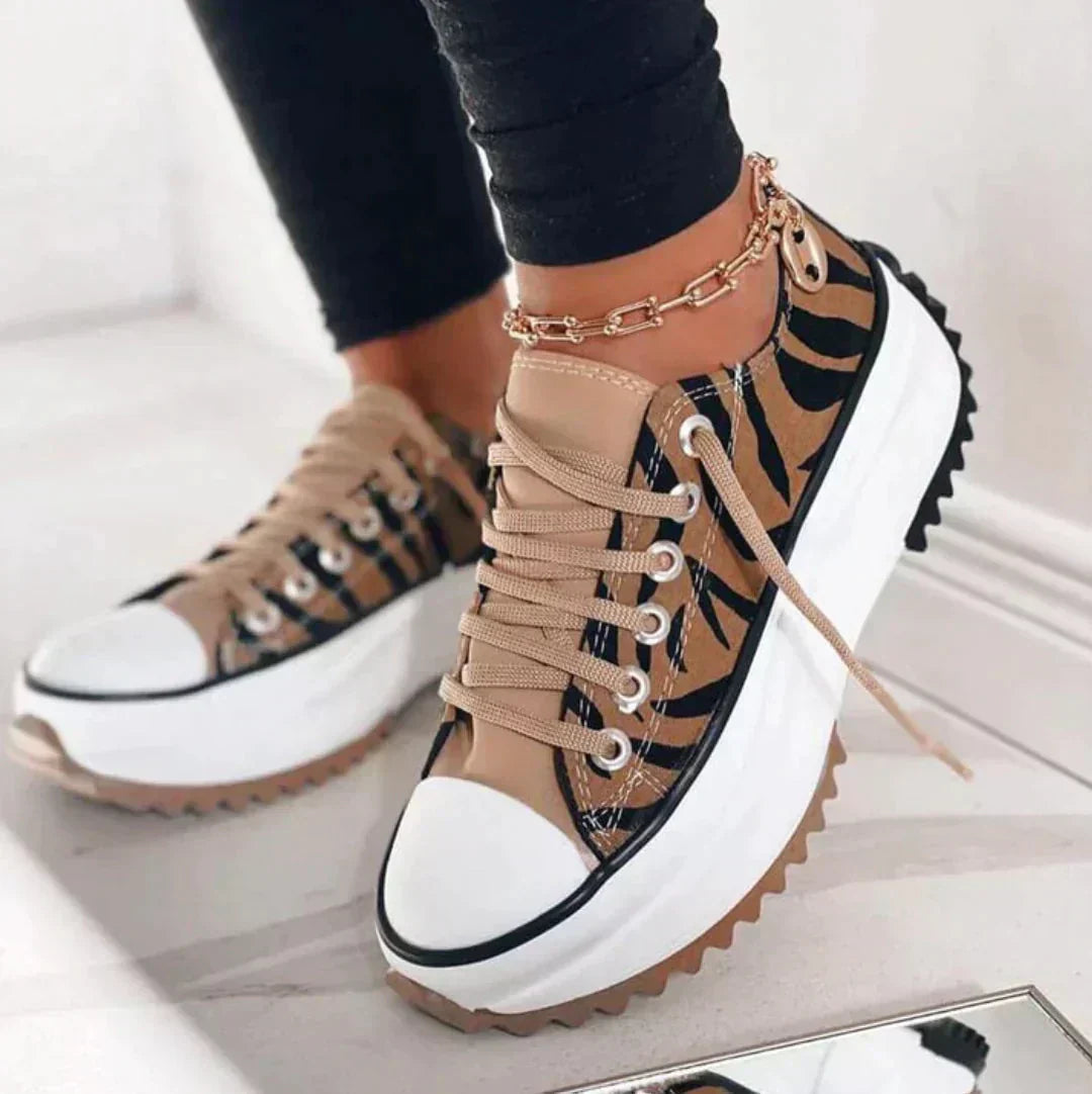 Lea Plateau-Sneaker mit beigem Zebra-Muster, weißer Plateausohle, Schnürung und markanter, gezackter Laufsohle.