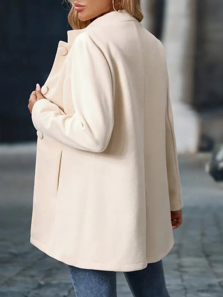 Beiger Damenmantel mit Stehkragen, Knopfleiste und tailliertem Schnitt für einen eleganten Look.