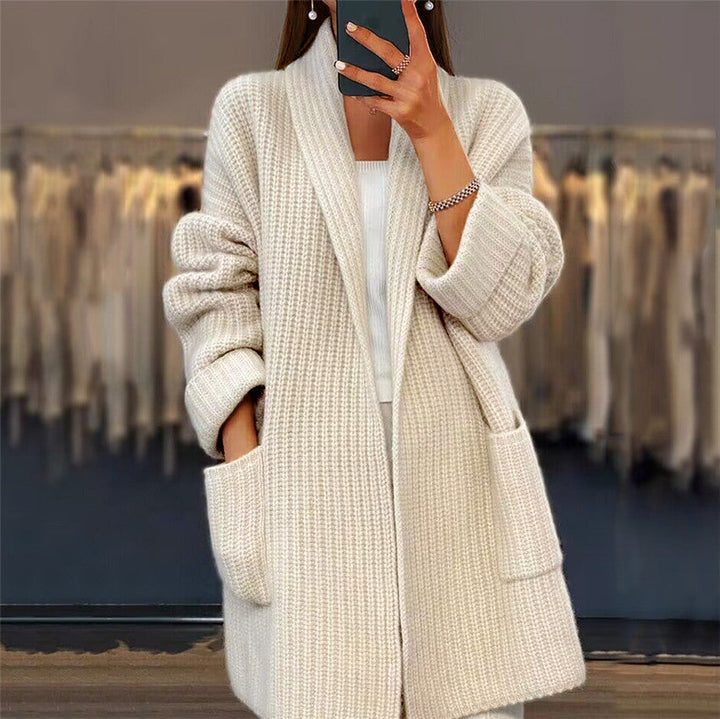 Beigefarbene, lange Damen-Strickjacke aus weichem Grobstrick mit elegantem Schalkragen und praktischen Seitentaschen.