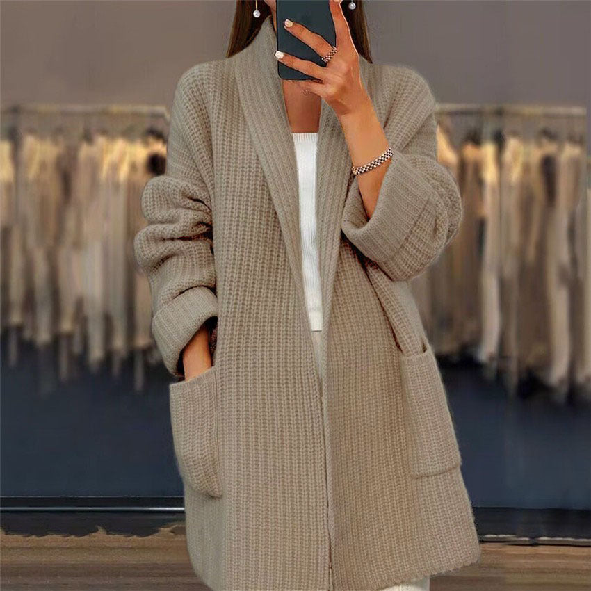 Beigefarbene, lange Damen-Strickjacke aus weichem Grobstrick mit elegantem Schalkragen und praktischen Seitentaschen.