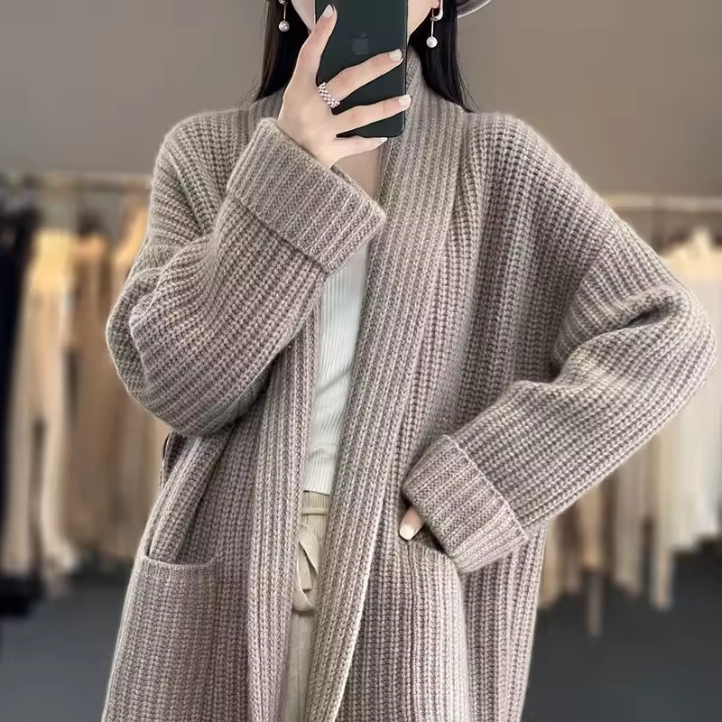 Lange, beige Grobstrick-Damenjacke mit Schalkragen, offenem Schnitt und praktischen Seitentaschen für einen lässigen Look.