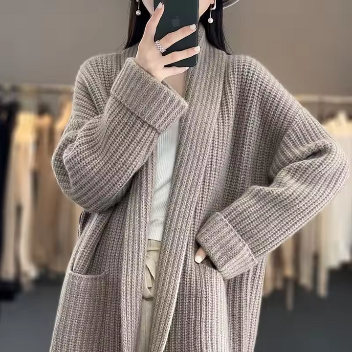Lange, beige Grobstrick-Damenjacke mit Schalkragen, offenem Schnitt und praktischen Seitentaschen für einen lässigen Look.