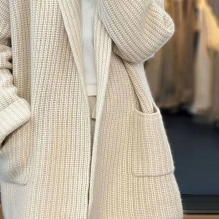 Beigefarbene, lange Damen-Strickjacke aus weichem Grobstrick mit offenem Schnitt, Schalkragen und praktischen Seitentaschen.